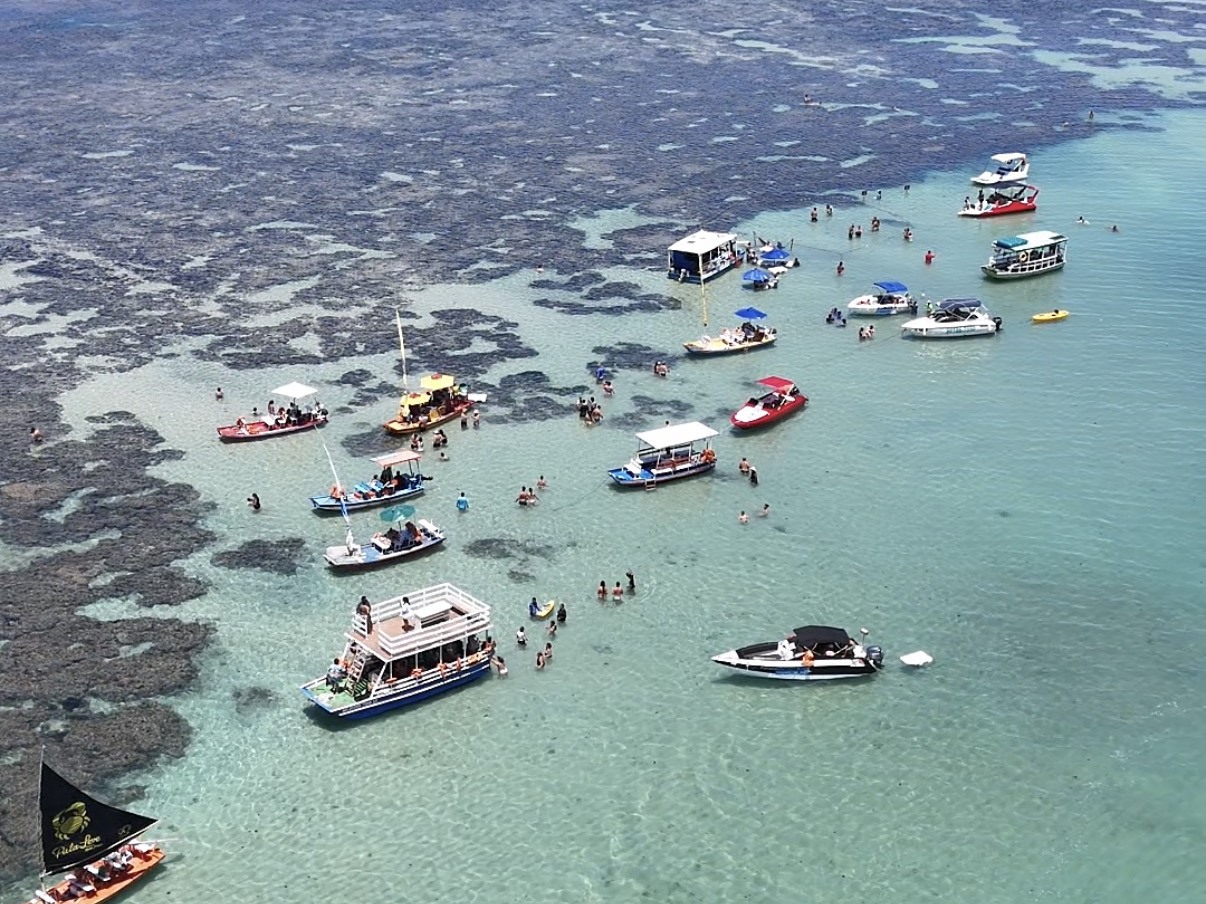 Vista aérea das piscinas naturais de Pajuçara com barcos e turistas, Maceió