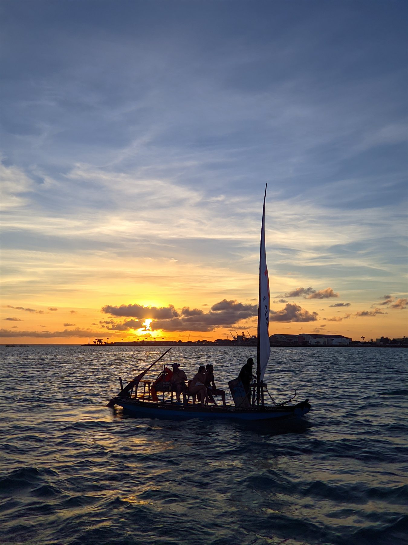Jangada em silhueta durante o pôr do sol sobre o mar de Maceió